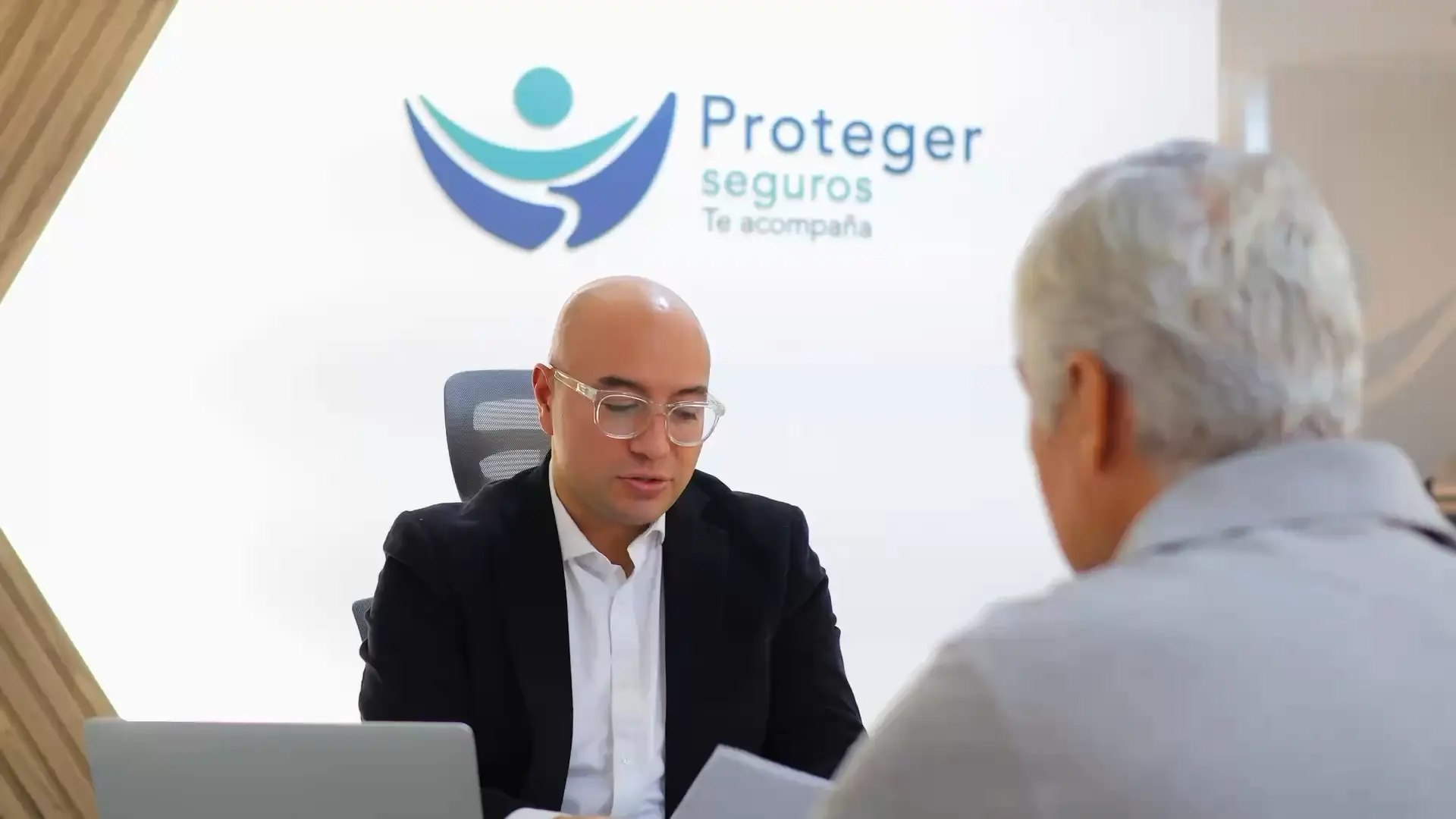 Un asesor de Seguros Proteger atiende a un cliente en la oficina